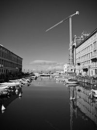 Buildings by river against sky in city