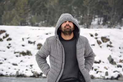 Young man wearing warm clothing standing in snow