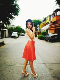 Portrait of young woman standing on street in city