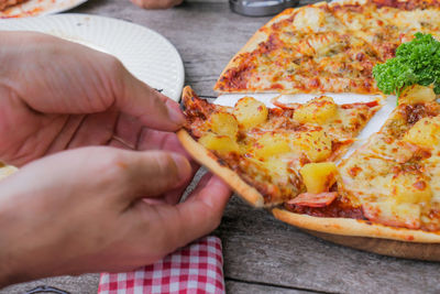 Cropped image of hand holding pizza