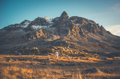 Astronaut standing on land against mountain