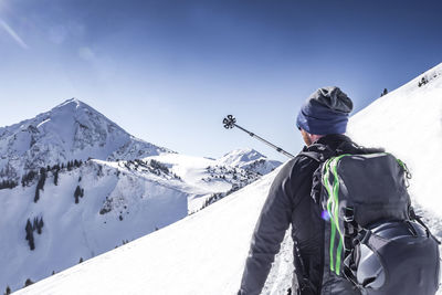 Rear view of woman skiing on snowcapped mountain against sky