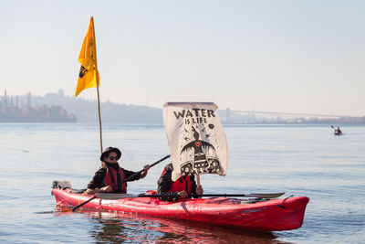 People on boat in sea against clear sky