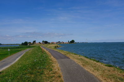 Road by sea against blue sky