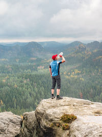 Rear view of woman standing on mountain against sky