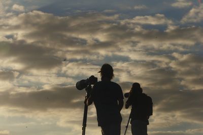 Rear view of people photographing against sky