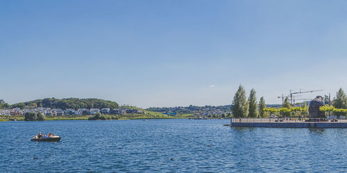 Boats sailing in river against blue sky