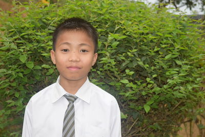 Portrait of boy in school uniform against plants