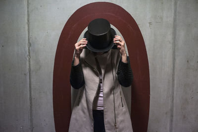 Full length of person wearing hat standing against wall