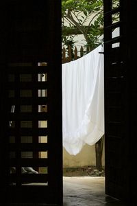 Fabric drying on clothesline seen through ajar house door