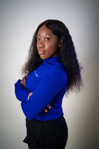 Portrait of young woman standing against white background