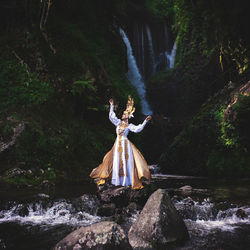 Woman looking at waterfall in forest