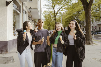 Portrait of smiling friends standing against building