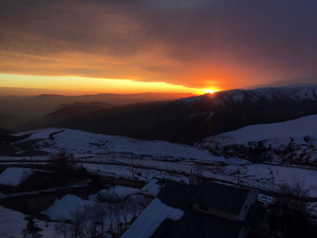 Scenic view of mountains against cloudy sky during sunset