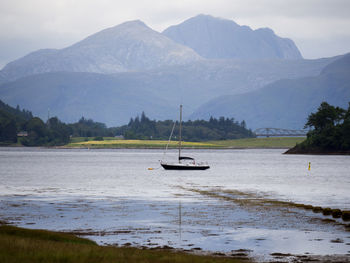 Boats in sea against mountains