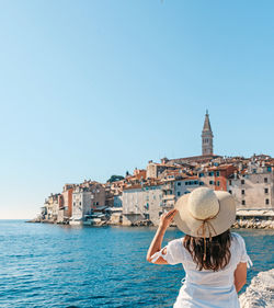 Rear view of woman against buildings against clear blue sky