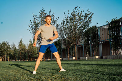 Portrait of young woman exercising on field