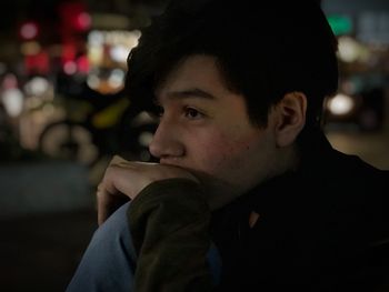 Close-up of teenage boy looking away at night