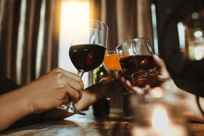 Midsection of woman and man hands  holding wine glass and whisky glass in night club