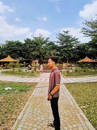 Full length of man standing on footpath against sky