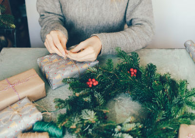 Woman makes a fir wreath and wrapping gifts for christmas. workshop crafting decorating. 