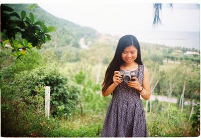 Young woman standing by plants against mountain