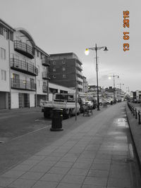 Cars on road by buildings in city against sky