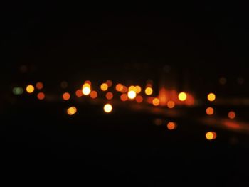 Defocused image of illuminated lights against sky at night