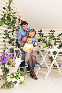 Full length of mother and daughter by potted plants against wall