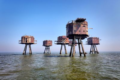 Lifeguard hut in sea against clear blue sky