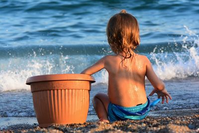 Rear view of shirtless boy on beach