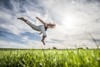 Man jumping on field against sky