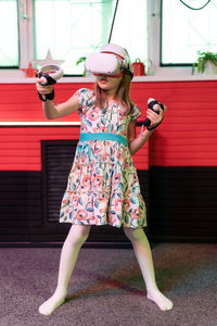 Full length of young woman standing against wall