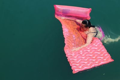 Woman with pool raft swimming in sea