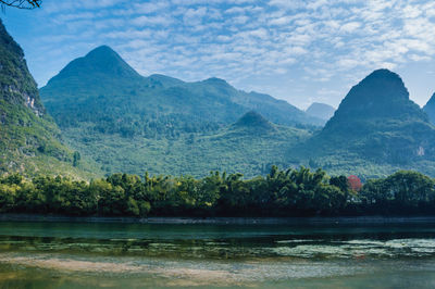 Scenic view of river by mountains against sky