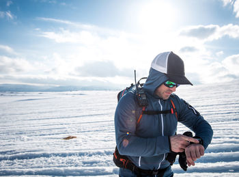 Man with radio checking his gps watch in snow