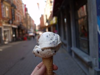 Close-up of hand holding ice cream cone on street