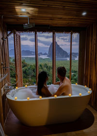 Couple sitting in bathtub while looking at landscape