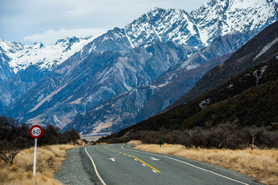 Road leading towards snowcapped mountains against sky