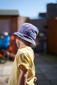 Turned around 2 years old boy with summer hat playing in his back yard.