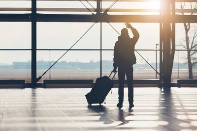 Silhouette of man at airport against sky