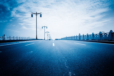 Road leading towards bridge against sky in city