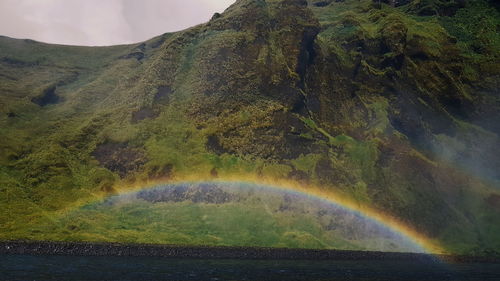 Scenic view of rainbow over mountain against sky