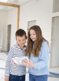 Smiling sibling looking at digital tablet at construction site