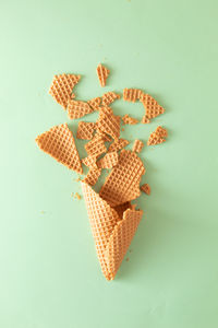 Shattered ice cream cone on pastel mint background. minimal food concept. flat lay.