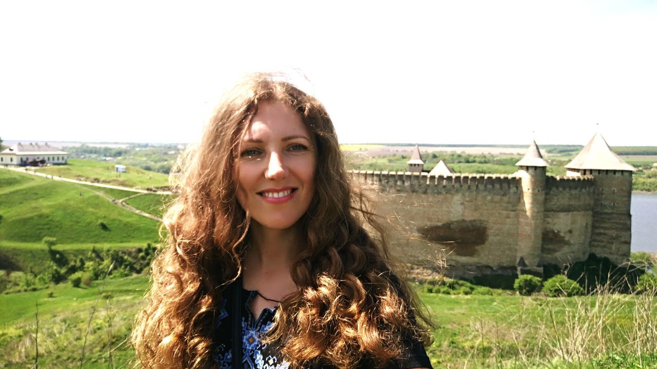 portrait, young adult, hair, one person, long hair, looking at camera, hairstyle, young women, smiling, front view, field, real people, sky, nature, lifestyles, happiness, leisure activity, day, beauty, beautiful woman, outdoors