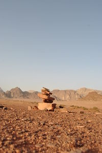 Stack of stones on field against clear sky