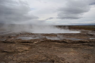 Scenic view of hot spring against cloudy sky