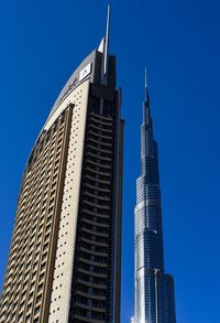 Low angle view of skyscrapers against clear blue sky