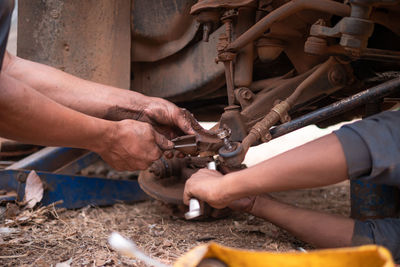 Cropped hands of mechanics repairing car in garage